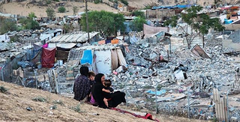 women-and-children-sit-on-a-hill-overlooking-a-destroyed-neighbourhood-in-gaza-56c8ba23cb6b124ee842eafee2dc5a4e1744864752.jpg