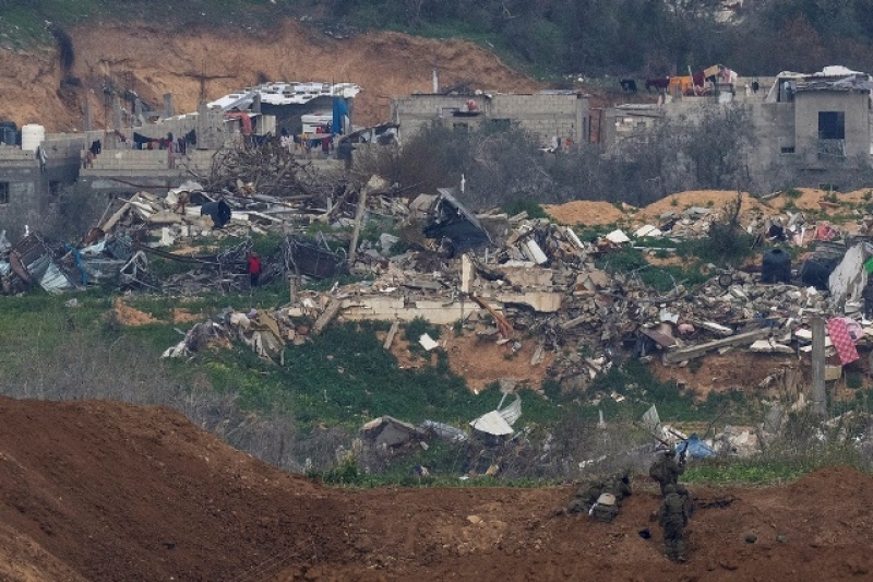 a-palestinian-man-wearing-a-red-shirt-left-stands-amidst-the-rubble-of-destroyed-buildings-watching-israeli-soldiers-bottom-right-take-position-in-the-northern-gaza-strip-feb-9-2025-248f62f57f97fd98c904ec3e874170961739245614.jpg